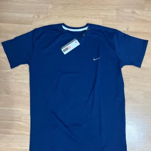 Marinblå Nike t-shirt  - Snygg marinblå t-shirt från Nike med klassisk rund hals och diskret logga på bröstet. Tillverkad i mjuk bomull som känns skön mot huden. Perfekt för dig som gillar enkel och stilren streetwear.