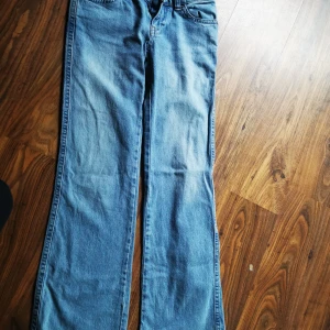 Bootcut jeans från Perfect Jeans, strl 34 - Snygga ljusblå bootcut jeans från Perfect Jeans i klassisk denim. Byxorna har fem fickor, bakfickor med lock och knapp, samt normal passform. Perfekta för dig som gillar en retroinspirerad look med lite utsvängda ben.
