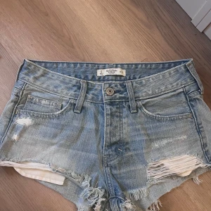 Ljusblå jeansshorts Abercrombie & Fitch - Snygga ljusblå jeansshorts från Abercrombie & Fitch med slitna detaljer och fransig kant. Lågmidjade och passar xs - s. Väldigt populära!