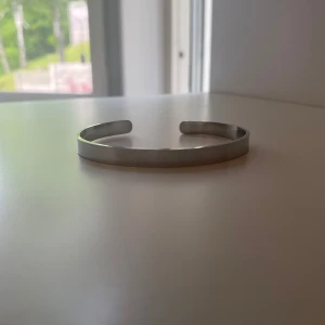 Silver armband - Säljer ett stilrent och minimalistiskt armband i silverfärg. Armbandet är stelt och öppet, vilket gör det lätt att ta på och av. Passar perfekt för dig som gillar enkel och tidlös design. Skriv till mig vid minsta lilla fundering!