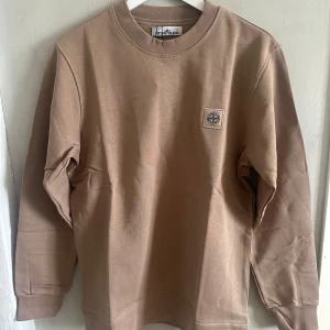 Crewneck från Stone Island - Säljer en  sweatshirt från Stone Island med rund hals och lång ärm. Tröjan har en diskret logotyp-patch på bröstet och är tillverkad i mjuk bomull. Perfekt för en stilren och avslappnad look.