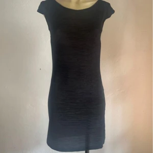 :Italiensk svart vintageklänning i ribbat tyg – figurnära & stretchig - Figurnära svart vintageklänning i stretchigt ribbat tyg med kort ärm och rundad halsringning. Tillverkad i Italien av mjuk viskosmix för både komfort och struktur. Märket är okänt men kvaliteten tydlig. Uppskattad storlek: Small (EU 36). Material: 95 % viskos, 5 % elastan. Priset är fast – jag prutar inte, men erbjuder gärna bundlerabatt.  Rensar garderoben – kika gärna på mina andra annonser också!  ⸻  