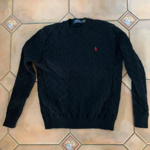 Svart kabelstickad tröja Polo Ralph Lauren - Helt ny Ralph lauren stickad tröja, använd en gång och tvättad en gång, blev lite mindre efter tvätt så skulle säga att storleken är mellan S och M.