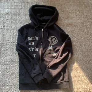 Svart hoodie med strassdetaljer från Blinglucid - Säljer min svarta blinglucid tröja med Eiffeltornet, i strl XS beställde den från deras hemsida för 700 kr, har använt den relativt mycket med den är fortfarande i fint skick
