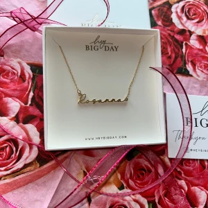 Guldfärgat namnhalsband Rosanna från Hey Big Day - Snyggt halsband i 14k guld plädering, med namnet 'Rosanna' i skrivstil. Kedjan är tunn och elegant, perfekt som personlig accessoar eller present. Levereras i en fin ask med rosigt tema. Nypris inkl frakt och tull ca 900kr. Helt nytt! Fick 2 stycken. 