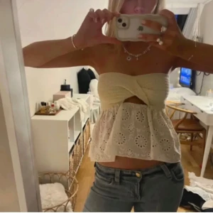 Beige axelbandslös topp - Snygg beige axelbandslös topp med omlott-design och broderade detaljer. Perfekt för sommardagar och festliga tillfällen. Kombinera med jeans eller kjol för en stilren look.