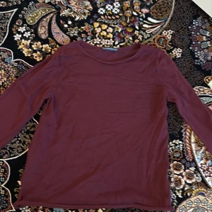 Vinröd långärmad tröja från Brandy Melville - En enkel och stilren vinröd långärmad tröja från Brandy Melville. Tröjan har rund halsringning och är tillverkad i ett mjukt material som passar perfekt till vardags. Snygg att styla med jeans eller kjol.