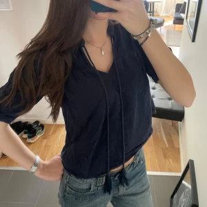 Mörkblå blus med knytning - Säljer en mörkblå blus med korta ärmar och v-ringning med knytband. Tröjan har en liten defekt under armhålan (be om bild) 🩵