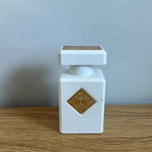 Inktio musk teraphy  - Exklusiv parfymflaska i vit matt finish med fyrkantig form och guldfärgade detaljer. Flaskan har en dekorativ guldplatta på framsidan och ett matchande lock med märkets logotyp. Lyxig och modern design.
