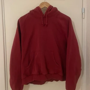 Röd hoodie från Stay - Säljer en röd hoodie från Stay med broderad logga på bröstet. Tröjan har huva med dragsko och en stor magficka. Perfekt för dig som gillar en avslappnad och enkel stil.
