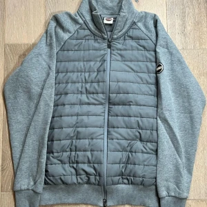 Grå quiltad jacka från Mavi - Säljer en grå jacka från Mavi med quiltad framsida och baksida samt mjuka ärmar. Jackan har dragkedja framtill och en liten logotyp på bröstet. Perfekt för lager-på-lager under kyliga dagar.