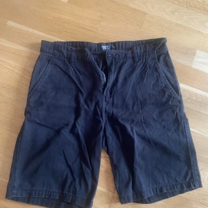 Svarta shorts från 157 - Svarta shorts från 157 med klassisk passform. De har fickor på sidorna och hällor för bälte. Materialet känns som bomull och de har dragkedja framtill. Perfekta för varma dagar.
