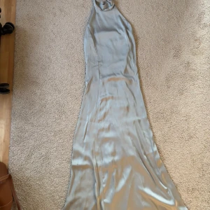 Satinklänning  - Blå/grå satinklänning i storlek XXS endast använd en gång. Superfin till fest, men även bal eller brudtärna. Är i behov av en tvätt, finns några mindre fläckar (se bilder). Även några lösa trådar på vissa ställen (se bilder). Varken fläckarna eller trådarna är något man lägger märke till. 