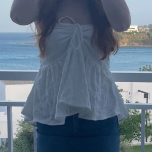 Vit axelbandslös topp med knyt - Säljer en söt vit axelbandslös topp med knyt framtill och volangig nederdel. Är en kjol passar som både topp och kjol☺️