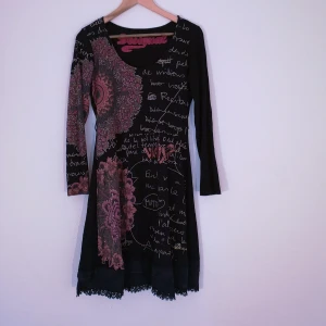 Desigual klänning strl L - Svart urringad Y2K klänning från Desigual med coolt tryck i rosa, rött, grått och sparkly detaljer, några rhinestones har lossnat vilket syns på bild 3. Finns band för skärp i midjan, står strl L men sitter fint på S-M med. Längd 91,5cm, runt midja 76cm, stretchig. Slutar precis ovanför knäna på mig som är 165cm. Bör endast handtvättas kallt eller lämnas till kemtvätt. Kan ta fler mått eller bilder vid intresse! 