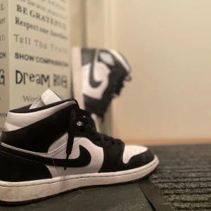 Nike Air Jordan 1 svartvita sneakers - Säljer ett par klassiska Nike Air Jordan 1 sneakers i svart och vitt. Skorna har högt skaft, snörning och den ikoniska swoosh-loggan på sidan. Perfekta för dig som gillar streetwear och vill sticka ut med en tidlös modell. Köpta från zalando och använda ett par gånger, pris kan diskuteras