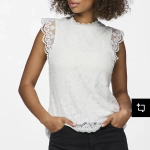 Vit spetsblus med volangdetaljer - Säljer en söt vit blus med spets och volangdetaljer vid axlarna. Blusen har hög halsringning och är ärmlös med fina spetskanter.