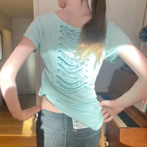 Turkos t-shirt med spetsdetaljer i ryggen - Snygg T-shirt i turkos färg. Har coola ”klippningar” eller vad man ska säga i ryggen med spets som syns under. As cool, ger väldigt mycket 2000 vibe. Skulle säga att den kanske är en S typ men jag bär xs och den sitter så på mig. Passar nog M bra också