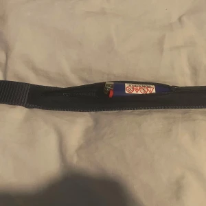 Blått bälte med dold ficka - Säljer ett blått bälte med en smart dold ficka med dragkedja, perfekt för att förvara småsaker. Bältet är enkelt och stilrent, passar till jeans eller andra byxor. Praktiskt och diskret till vardags.