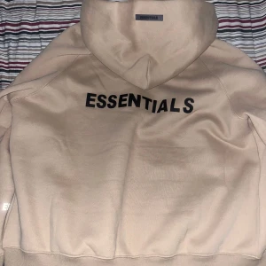 Essentials hoodie med dragkedja - Säljer en beige hoodie från Essentials med svart logga på luvan, ryggen och handleden. Säljs eftersom den inte passar mig, jag har storlek M och tröjan är i storlek L. Den är självklart autentisk och kommer med kvitto. Använd 2 gånger. Pris kan diskuteras vid köp samma dag.