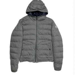 Grå Moncler morel jacka, äkta! - En härlig grå Moncler Morel jacka i storlek 2 motsvarar S, den har sin efterliknelse från modellen moncler Montgenevre då det är samma material bara att denna är tunnare och mer en vår och höst jacka, jackan köptes i april 2024 på kaspersheat, ni får gärna ta en titt på deras instagramsida och hemsida så att ni ser att det är legit, har ett online kvitto på den. Svarar gärna på frågor så ställ på, skicket skulle jag säga är 8/10 då den inte har några defekter men tecken på användning.