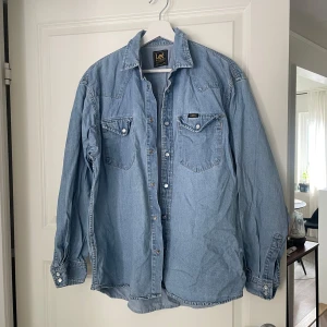 Ljusblå jeansskjorta från Lee - Säljer en klassisk ljusblå jeansskjorta från Lee i storlek M.  Knappt använd, fint skick