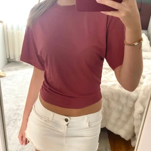 Mörkröd croppad t-shirt - Säljer en mörkröd/rosa croppad t-shirt med korta ärmar. T-shirten har en enkel och stilren design, perfekt att matcha med jeans eller shorts. Materialet känns mjukt och bekvämt mot huden.