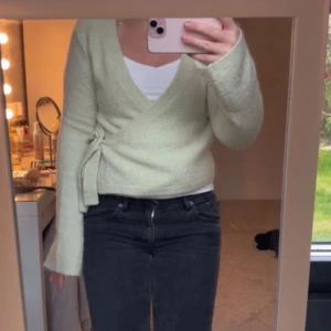 Ljusgrön omlottkofta från Gina Tricot - Säljer en ljusgrön stickad omlottkofta från Gina Tricot. Koftan har v-ringning, knyt i sidan och långa ärmar. Perfekt att styla med ett linne under. Supermjuk och skön!