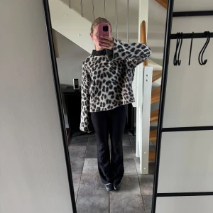 Leopardmönstrad stickad tröja med vida ärmar - Säljer en mysig stickad tröja med leopardmönster i svart och beige. Tröjan har vida, långa ärmar. 