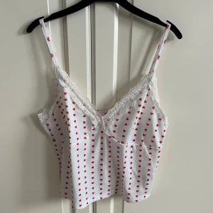 Hjärtlinne - Supersött linne med massa små röda hjärtan. Spetsdetalj längs kanterna upptill. Jättebra skick. Storlek xs🩷