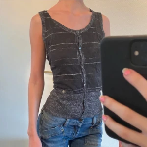 Svart glittrigt linne - Säljer en svart ärmlös linnetopp med smala vita ränder och knappar framtill. Den är glittrig och passar bra till jeans! Storlek L, men passar mig som har S. Jag på bilden är 178 ❤️