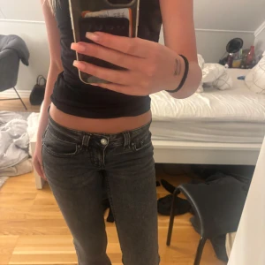 Grå jeans med låg midja - Säljer ett par grå jeans med låg midja och klassisk femficksdesign. Jeansen har raka ben och silverfärgade knappar och nitar. Perfekta för en avslappnad stil och passar till det mesta i garderoben. jag är 170cm lång 
