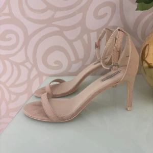 Klackar från NLY Shoes - Klackar med smal rem över tårna och runt vristen från NLY Shoes. Skorna har öppen tå och en elegant klack, perfekta för att lyfta din outfit.