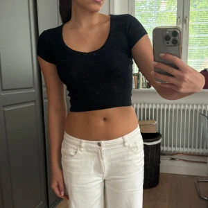 Svart croppad topp med kort ärm XS - Säljer en svart croppad topp med rundad halsringning och korta ärmar. Toppen är tight och har en enkel, stilren design som passar perfekt till både jeans och kjol.