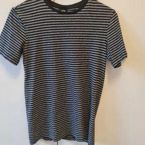 Randig t-shirt från H&M strl XS - Säljer en svart och grå randig t-shirt från H&M. T-shirten har rund halsringning och är tillverkad i 100% bomull. Storlek XS. Kan hämtas i Vallentuna.