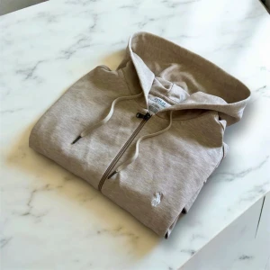 Beige hoodie från Polo Ralph Lauren - Säljer en beige hoodie från Polo Ralph Lauren i storlek M. Tröjan har dragkedja framtill, huva med snörning och en liten broderad logga på bröstet. Perfekt för en avslappnad och stilren look.
