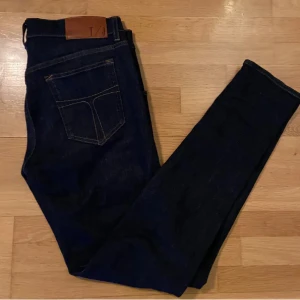 Mörkblå jeans med läderpatch - Säljer mina mörkblå tiger of sweden jeans i stl 31/32. jeansen har smal passform och raka ben. Sparsamt använda och i mycket fint skick.