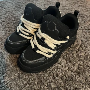 Zara x Lanvin skor - Säljer ett par svarta sneakers från Zara med kraftiga vita snören och tydliga vita sömmar. Skor perfekta till Streetwear stil. Skateskor kallas sånn här typ av sko