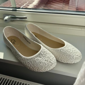 Vita spetsballerinaskor  - Säljer ett par vita ballerinaskor från Clou med vackert spetsmönster. Skorna har rund tå och platt sula, perfekta för en somrig look. De är lätta och har en feminin design med fina detaljer i spets. Från din sko nypris 250 🩷aldrig använda 