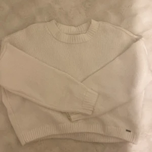 Vit stickad tröja från Hollister - Säljer en vit stickad tröja från Hollister. Tröjan har en klassisk rund halsringning, ribbade muddar och är långärmad. Perfekt för lager-på-lager och enkel att matcha med olika outfits. Knappt använd
