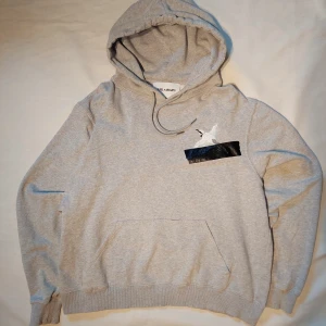 Grå hoodie från Axel Arigato - Stilren och bekväm hoodie från Axel Arigato i en tidlös grå färg. Storlek S. Mjuk, högkvalitativ bomullsblandning med minimalistisk design och diskret logga på bröstet. Perfekt både till vardags och för en avslappnad streetwear-look.  ✅ Mycket fint skick – inga fläckar, hål eller noppor ✅ Mjuk och skön att bära ✅ Svenskt streetwear-märke med fokus på kvalitet och stil ✅ Från rök- och djurfritt hem  En riktigt snygg och mångsidig hoodie för dig som gillar stilrena basplagg.