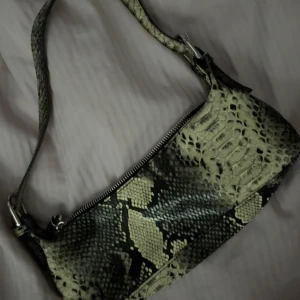 Axelväska i ormmönstrat skinn - Säljer en snygg axelväska i ormmönstrat skinnimitation med dragkedja upptill. Super snygg, näst intill oanvänd🩷💛Säljer pågrund av att den ej kommer tillanvänding då jag har massvis med väskor🙏🏼👜