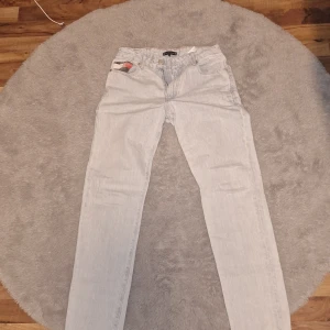 Ljusblå jeans från Tommy Hilfiger - Säljer ett par ljusblå jeans från Tommy Hilfiger med klassisk femficksdesign och raka ben. Byxorna har en liten Tommy Hilfiger-logga på bakfickan och patch med varumärket vid linningen. Perfekta för en avslappnad stil. Råkar dock ha ett litet hål i ena bakfickan