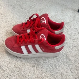 Röda Adidas Campus sneakers - Säljer ett par röda Adidas Campus sneakers med vita ränder och vit sula. Skorns är köpta för 1 år sen och inte alls mycket används ca10 ggr!