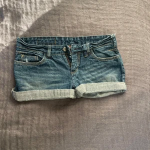 Lågmidjade jeansshorts  - Säljer ett par snygga och trendiga jeansshorts med låg midja från Vero Moda. De är mörkblåa och har unika detaljer. Shortsen är lite för små för mig som man ser i annonsen och jag har vanligtvis storlek M. Dessa är i S. Perfekta för sommaren!