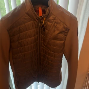 Beige lättviktsjacka från Parajumpers - Säljer en beige lättviktsjacka från Parajumpers med quiltad framsida och rygg. Jackan har dragkedja, lång ärm och en klassisk patch på ärmen. Perfekt för dig som vill ha en stilren och sportig look.