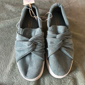 Gröna slip-on sneakers från Pernilla Wahlgren - Snygga gröna slip-on sneakers från Pernilla Wahlgren med twistad detalj framtill. Skorna har vit platt sula och är tillverkade i mocka. Perfekta för dig som vill ha både stil och komfort i vardagen.
