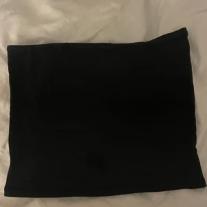 Svart tubtopp från NA-KD - Säljer en enkel och stilren svart tubtopp från NA-KD i storlek XXS. Perfekt att matcha med både jeans och kjol för en trendig look. Mjuk och stretchig känsla.