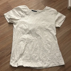 Vit t-shirt från Take Off - En klassisk vit t-shirt från Take Off i storlek L. T-shirten har rund halsringning och korta ärmar, perfekt för en enkel och stilren look. Tillverkad i mjuk bomull som känns skön mot huden.