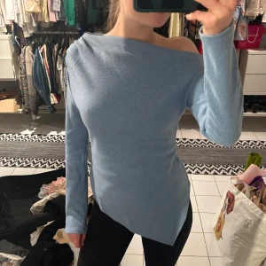 Ljusblå asymmetrisk offshoulder tröja - Säljer en ljusblå långärmad tröja från Zara med asymmetrisk nederkant och offshoulder-design. Tröjan är ribbad och har en tight passform som framhäver figuren. Perfekt för dig som vill ha något unikt och stilrent i garderoben. Använd 1 gång.